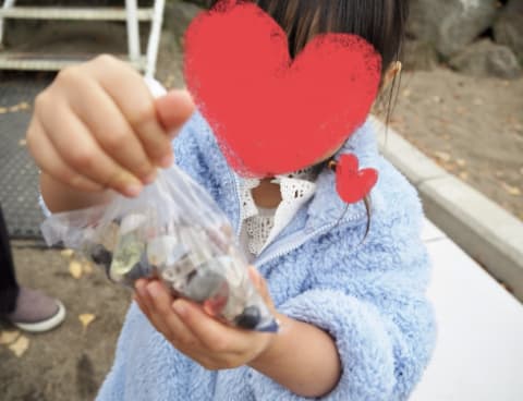 いくつか宝石の入ったビニール袋を子どもが手に持っている