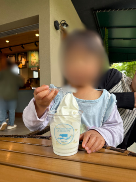 子どもがスプーンを手に持ち、ソフトクリームを食べようとしている