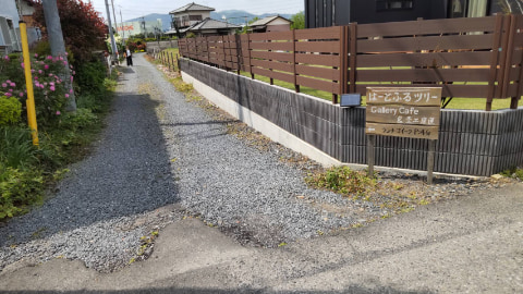 狭い道路の曲がり角にカフェの案内看板が立っている
