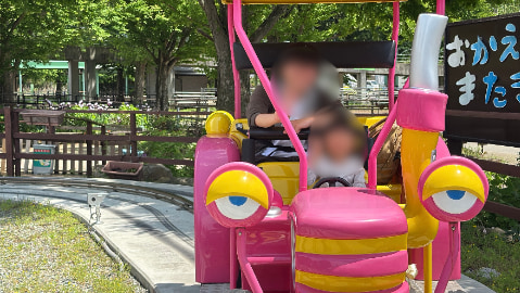 女の子が自動車型のアトラクションに乗っている