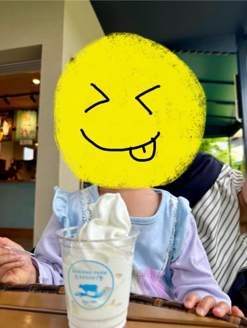 子どもがスプーンを手に持ち、ソフトクリームを食べようとしている