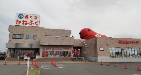 かねふくめんたいパークという建物の外観写真で、建物の上には赤いキャラクターが乗っている