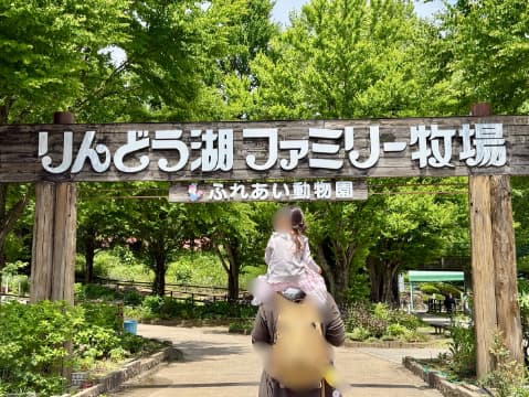 牧場の入り口で女の子がお父さんに肩車されている