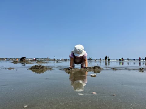 子どもが砂浜でしゃがんでいる