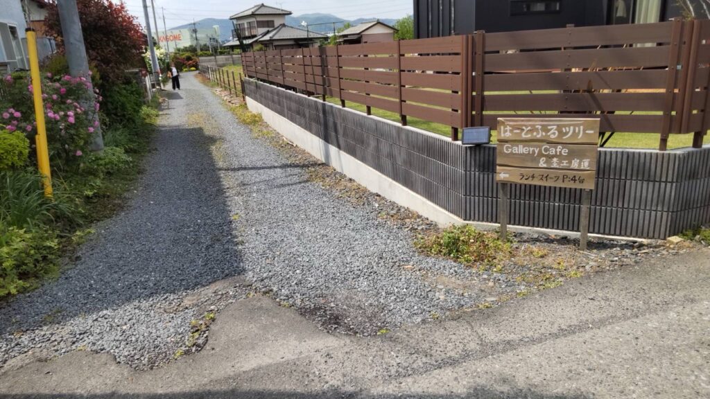 狭い道路の曲がり角にカフェの案内看板が立っている