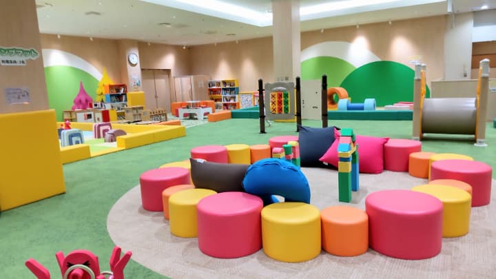 カラフルな円柱のイスが並べて置かれている子ども用の室内遊び場