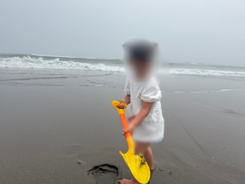 子どもが波打ち際でシャベルを持って遊んでいる