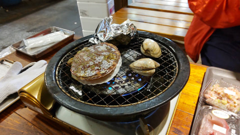網の上でハマグリやホタテが焼かれている