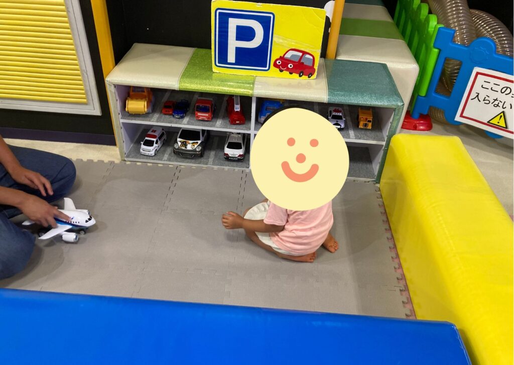 車のおもちゃの前にこどもが座っている