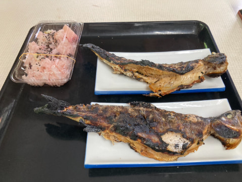 魚の塩焼きとご飯がお盆に乗っている